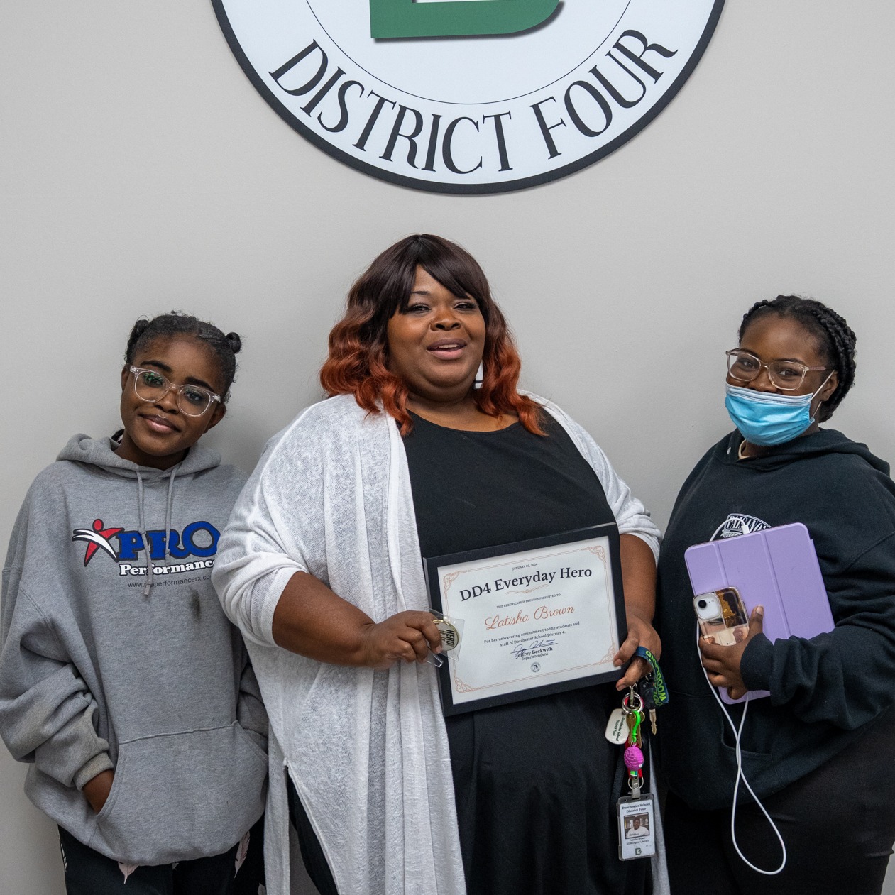 Latisha brown and family posing in below a DD4 logo after receiving the everyday hero award