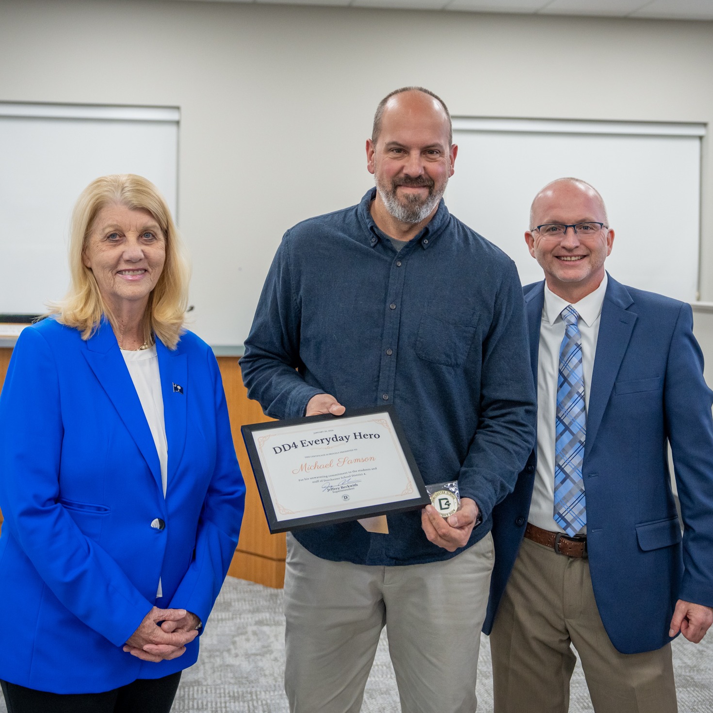 Michael Samson posing with Board Chair Phyllis Hughes and Superintendent Beckwith as Samson receives the Everyday Hero Award