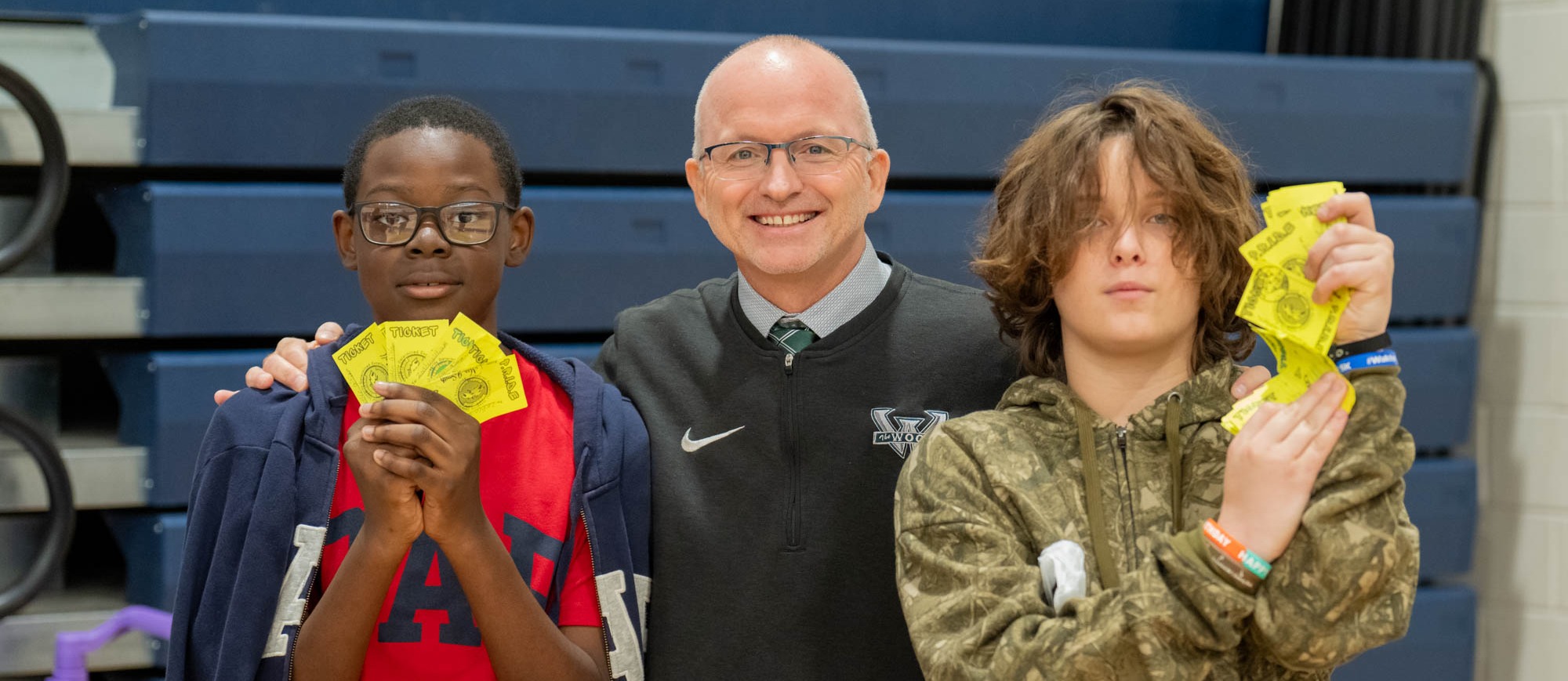 Superintendent Beckwith posing with two male Woodland Middle School students at the PBIS cash out. Students are holding up their PBIS tickets.