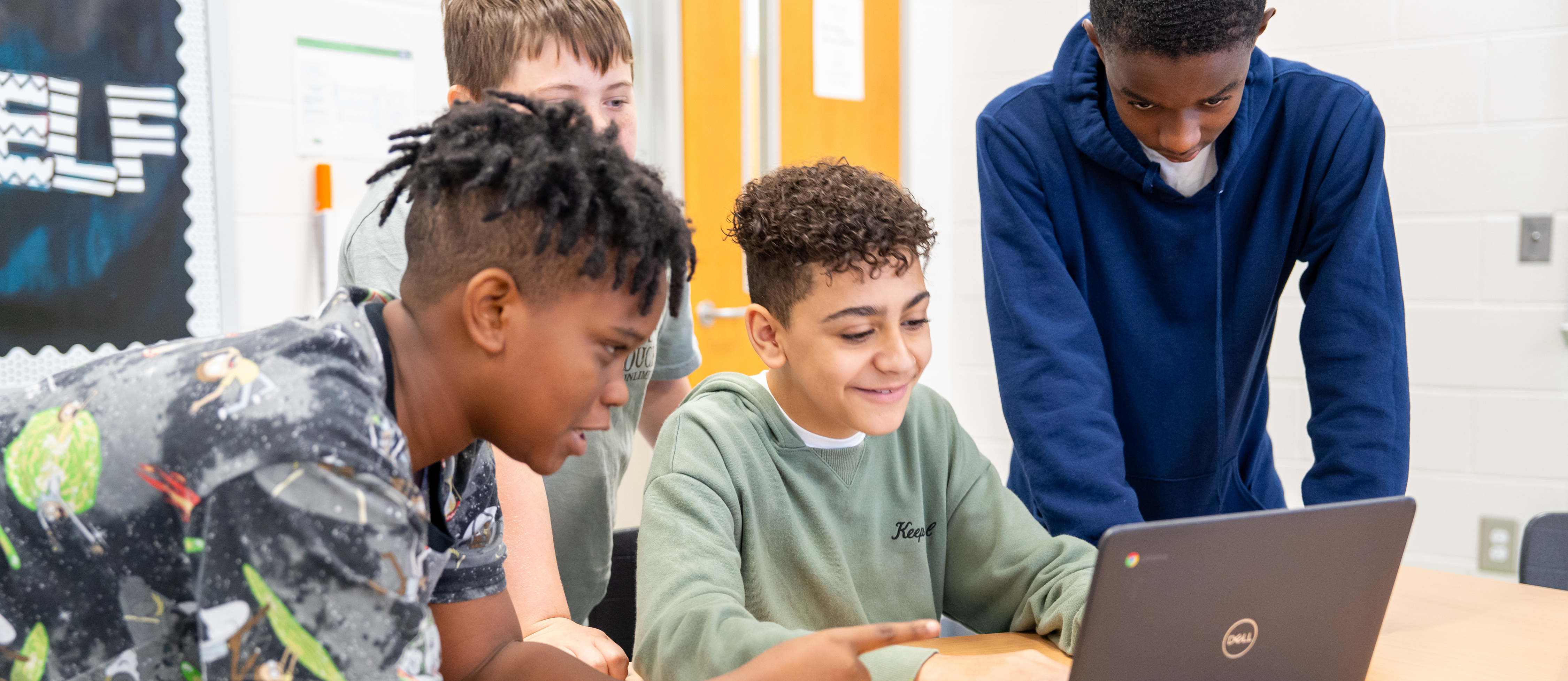 students editing project on computer in a group