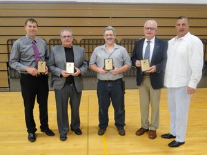 Five men proudly display their awards in a gymnasium, celebrating their achievements in a vibrant atmosphere.