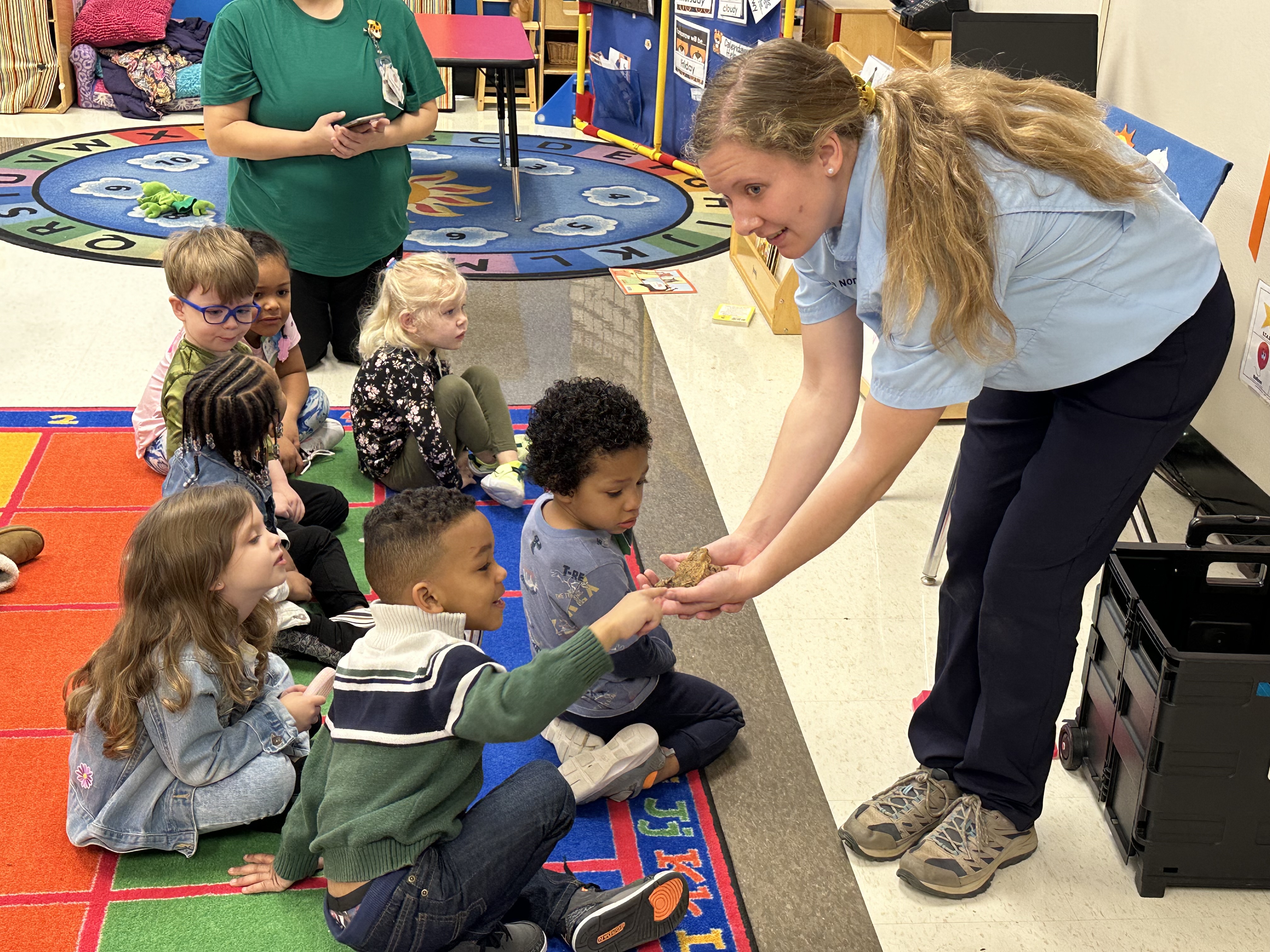 Students wait their turn to touch a frog, a visitor from the Missouri Department of Conservation