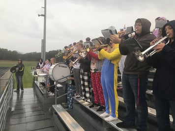 A diverse group of musicians standing on bleachers, holding various instruments.