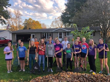 A group of people standing in front of a house with shovels.