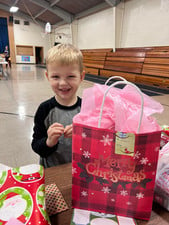 Boy happily holds Christmas gift bag.