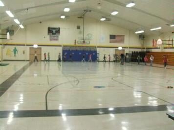 A basketball court with people playing basketball in it