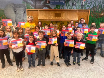 A group of children holding up colorful paintings