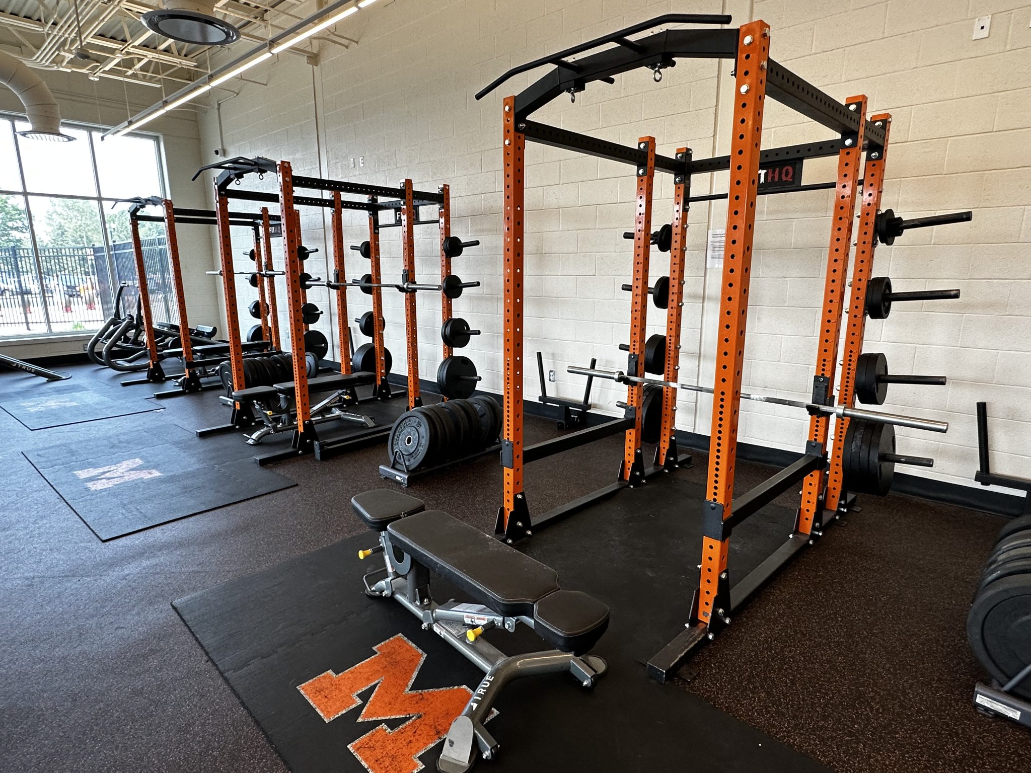 A well-equipped gym featuring various weights and fitness equipment arranged neatly in a spacious room.