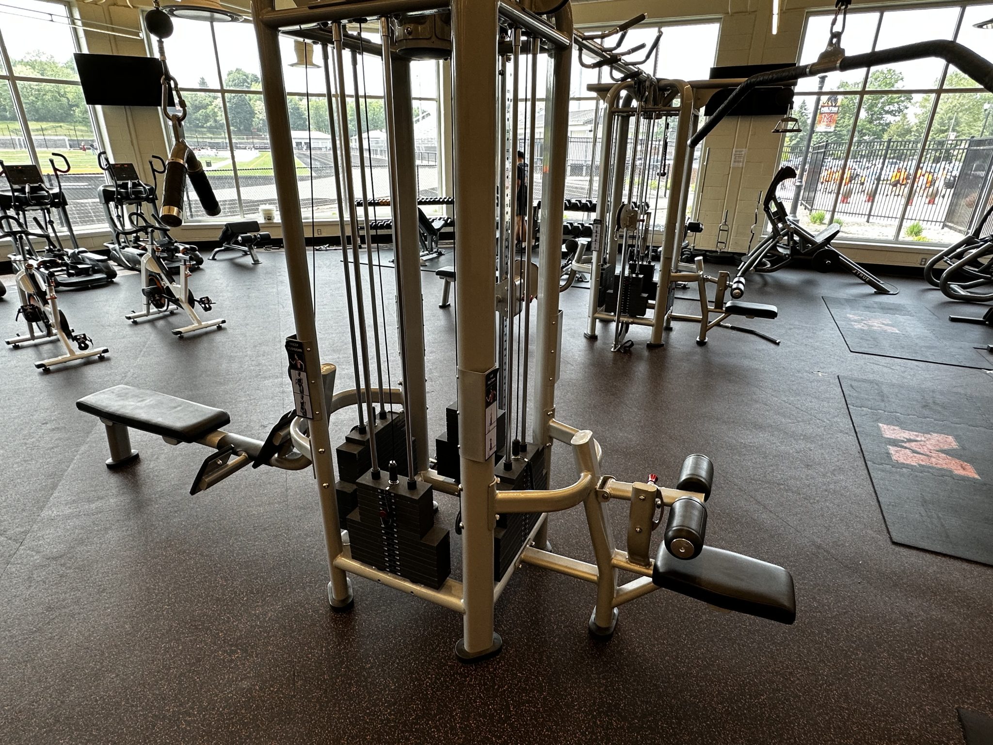 A bright gym featuring a row of exercise machines lined up beside a large window, inviting natural light inside.