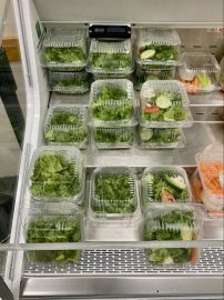 A refrigerator packed with fresh salad and various food items