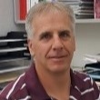 A man in a striped shirt sitting at a desk.