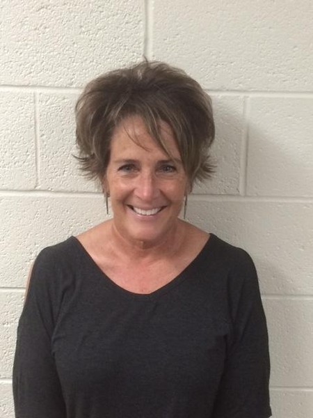 Woman in black shirt standing in front of white wall.