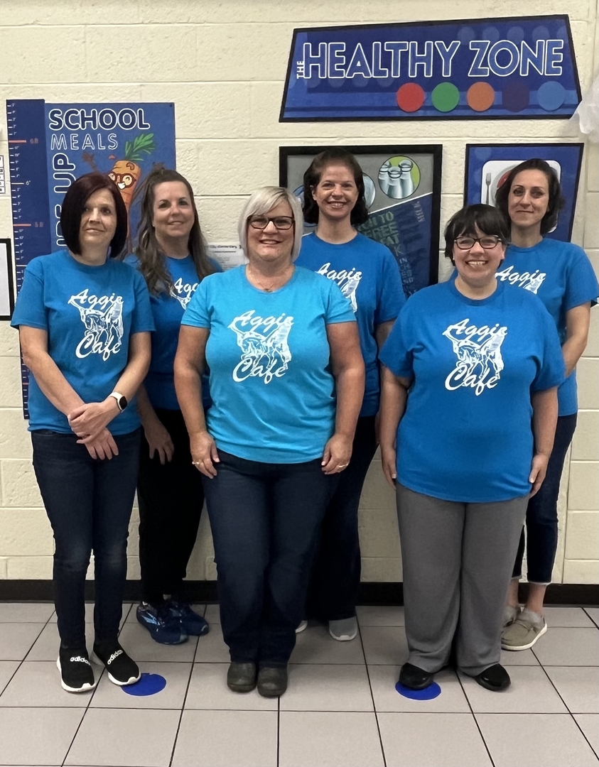 Several women in blue shirts posing in front of a wall.