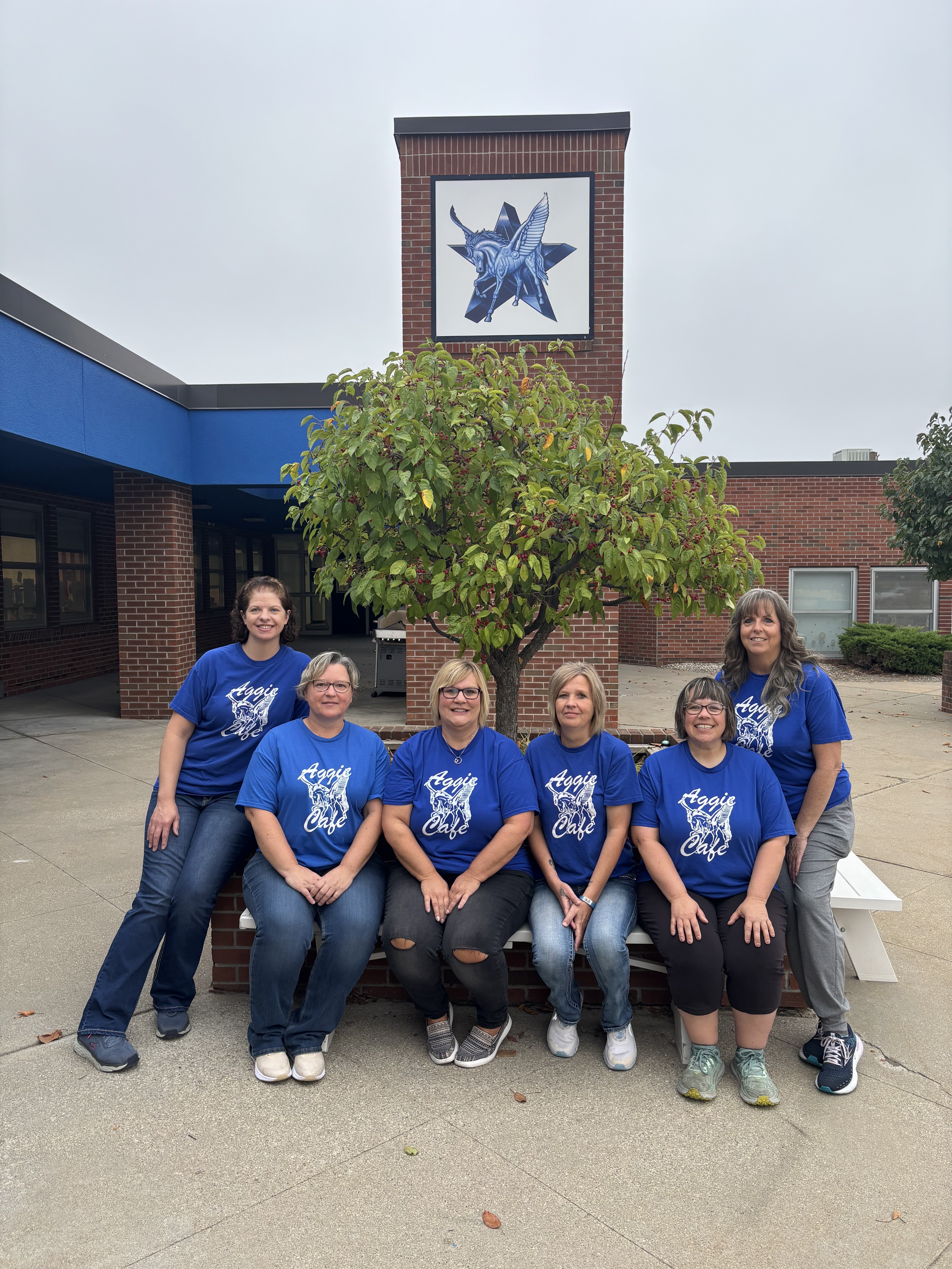 Several women in blue shirts posing in front of a wall.
