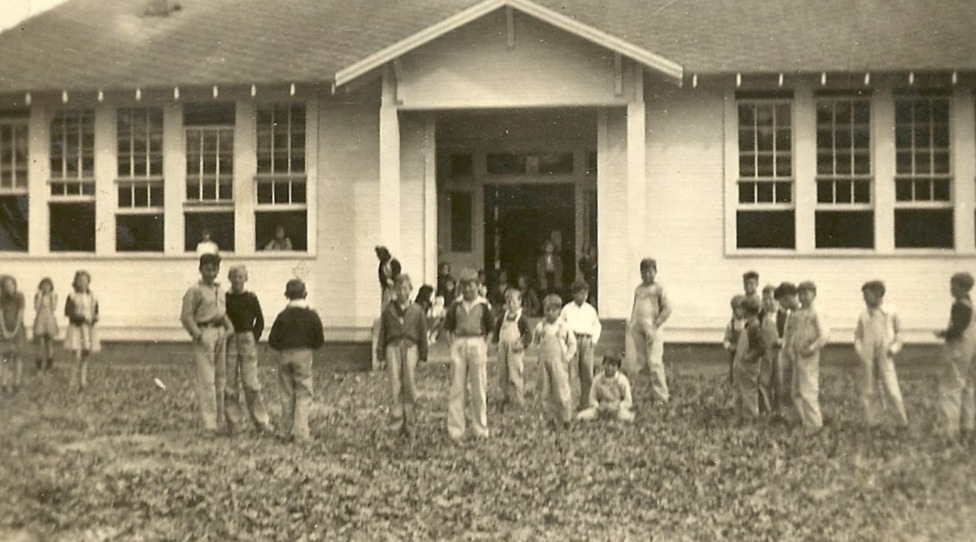 Old school building with children playing in front.