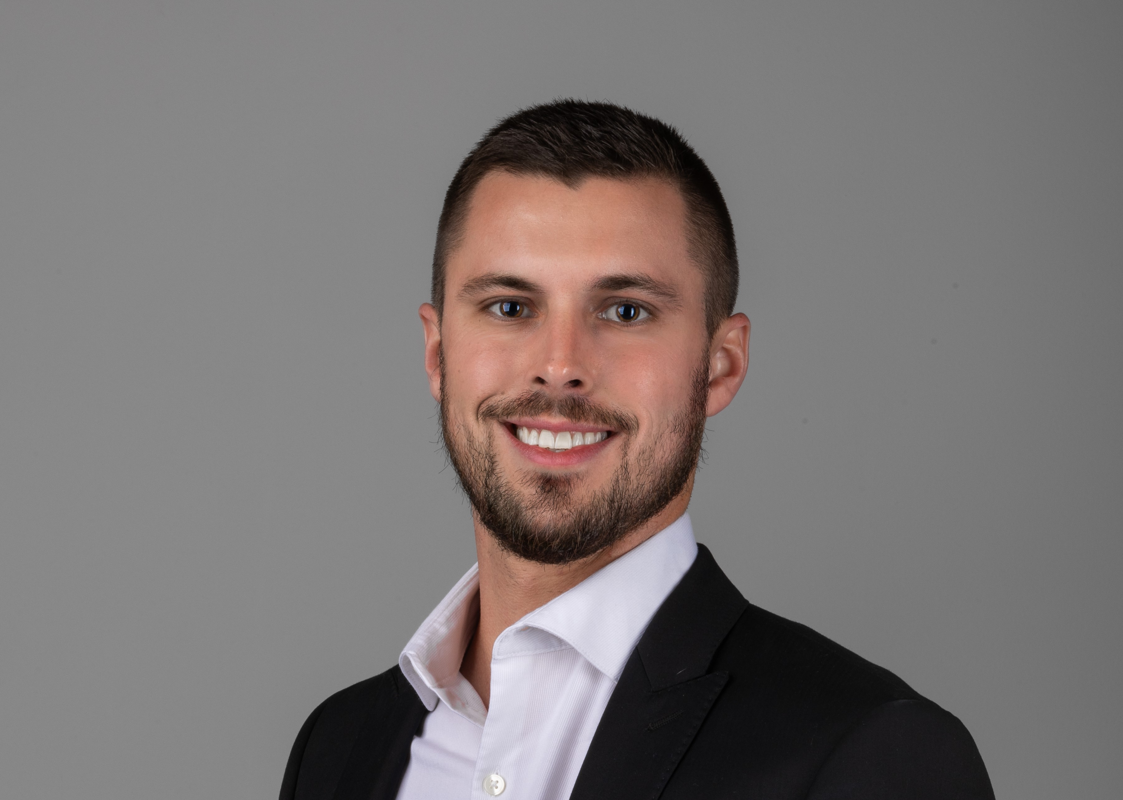 professional headshot of man in black suit