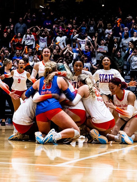 Volleyball team celebrating on the court.