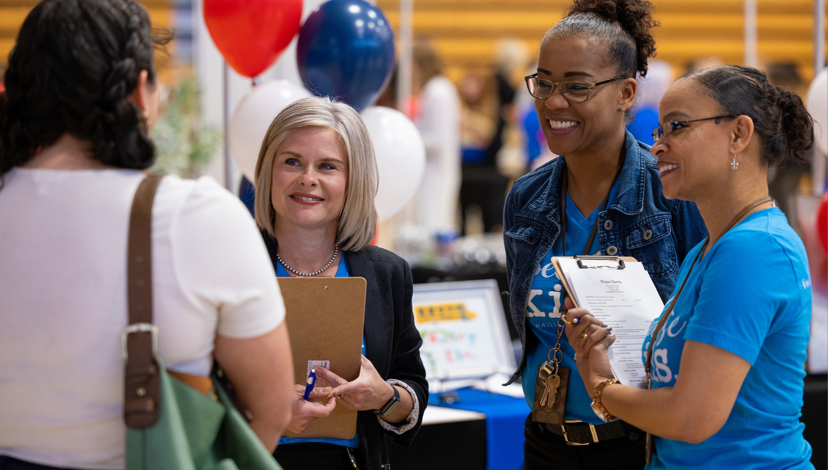 Employees talk to a candidate at a job fair.