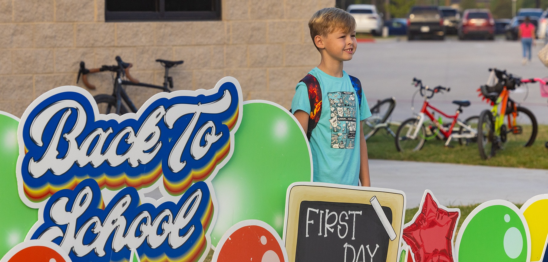 Boy standing behind a Back to School sign