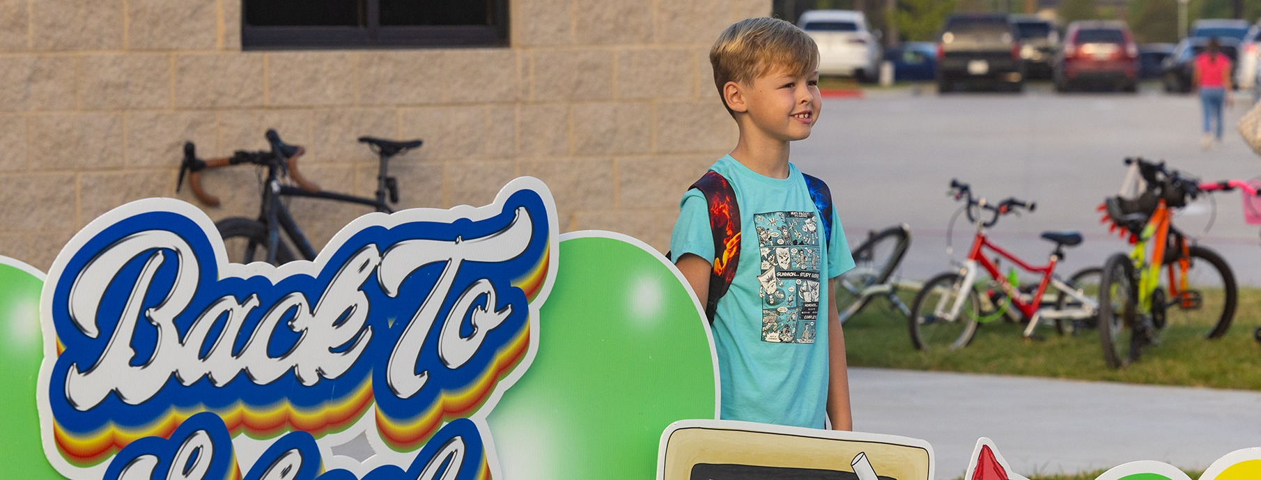 Boy standing behind a Back to School sign