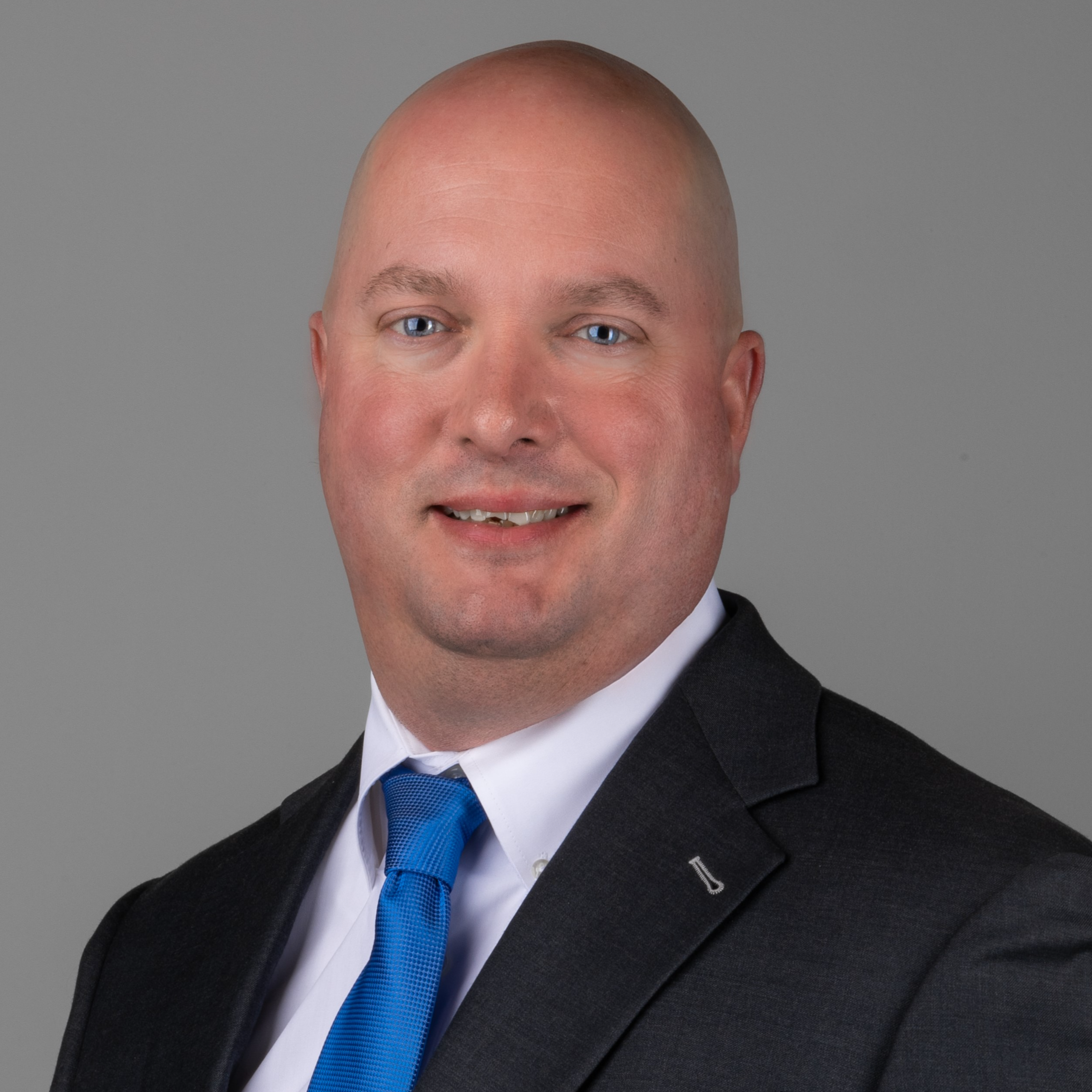 professional headshot of man in black suit