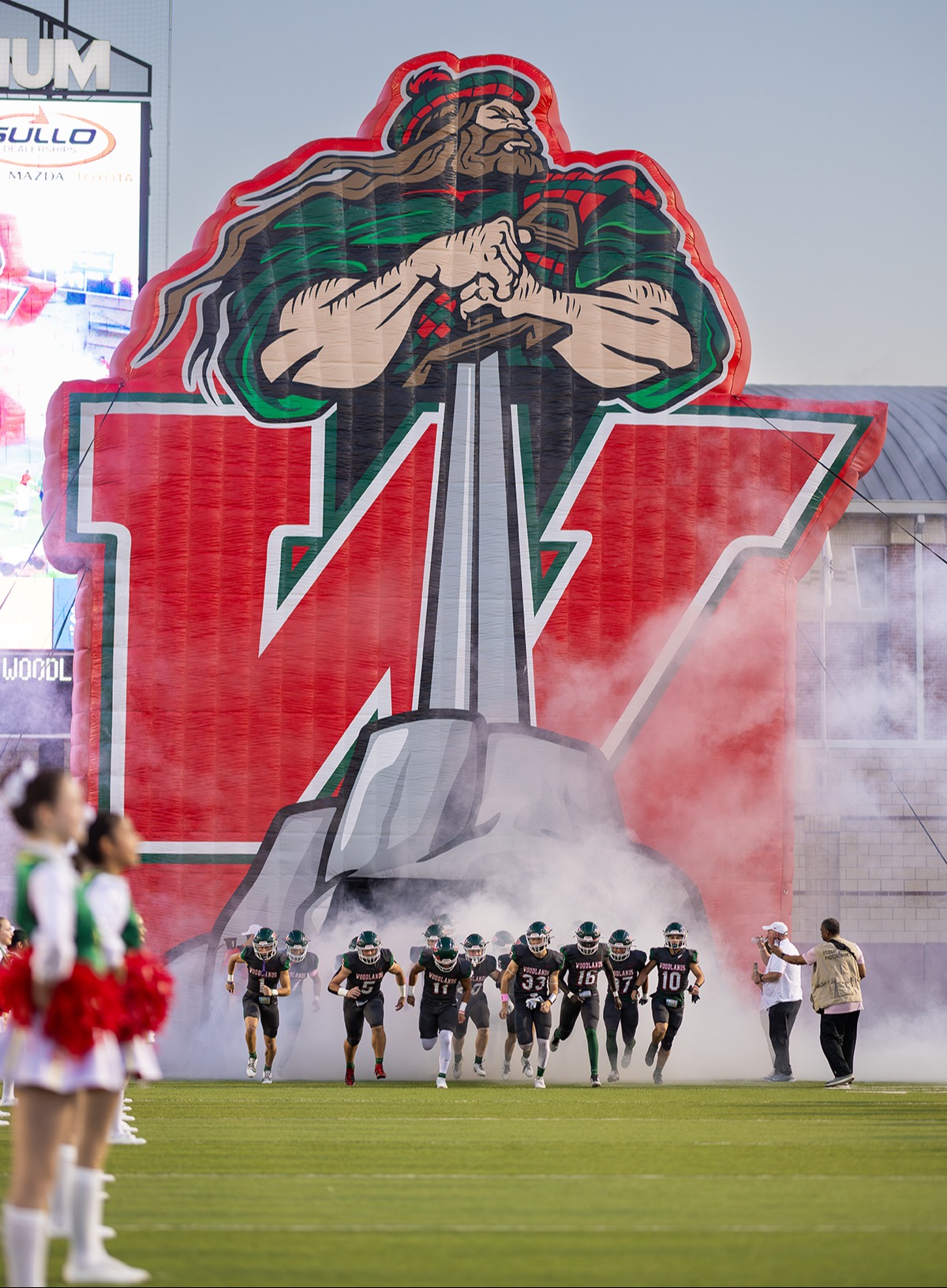 Highlander giant inflatable tunnel with football team running through smoke from opening at the bottom.