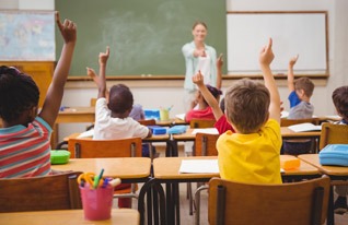 Students eagerly participating in class discussion, raising hands to answer questions.