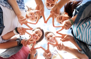 A group of young people smiling and forming a star shape with their hands, showing unity and teamwork.