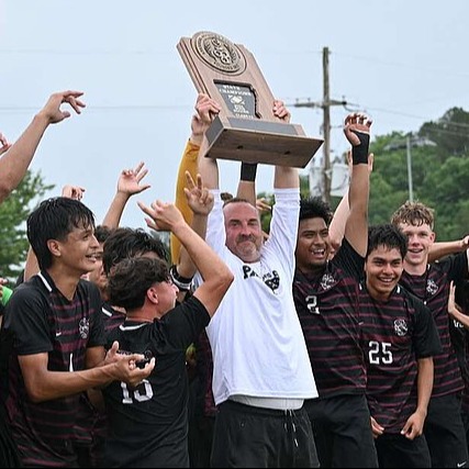 A group of soccer players, one holding a trophy, raising their hands in celebration; numbers 23, 10, 2, and 25 are on their shirts.