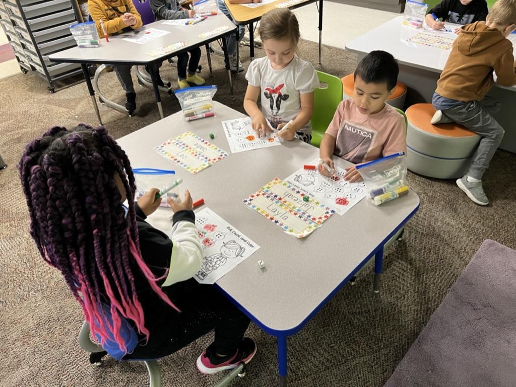 Young children sitting at a classroom table, engaged in an activity.