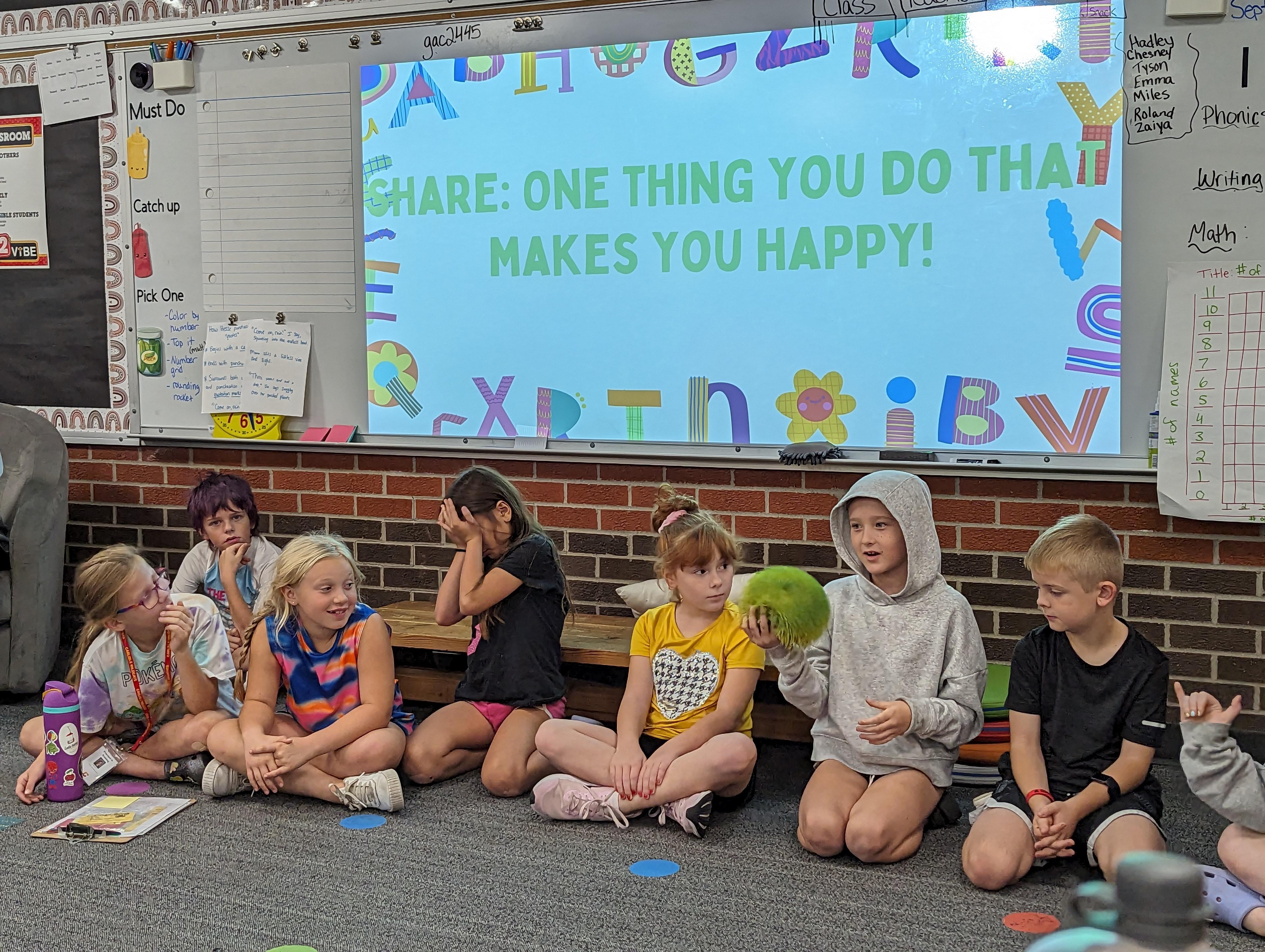 Young children sitting on the floor in a classroom.