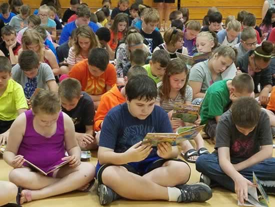 A diverse group of children sitting on the floor, deeply engaged in reading their favorite books together.