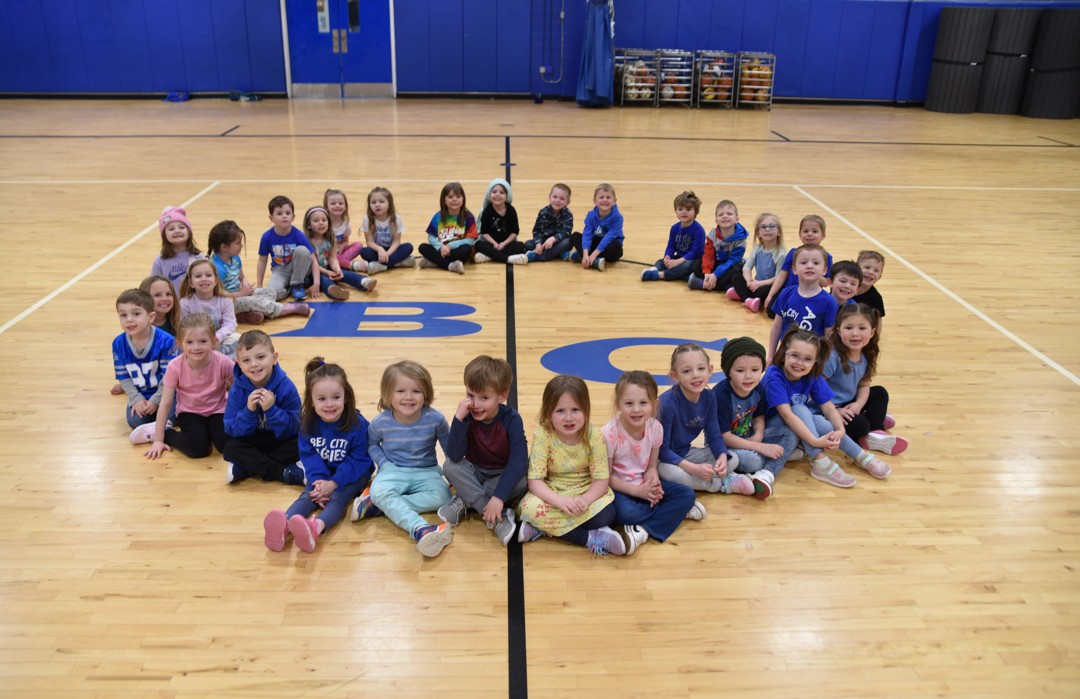 Elementary students sitting in a circle on the gym floor.