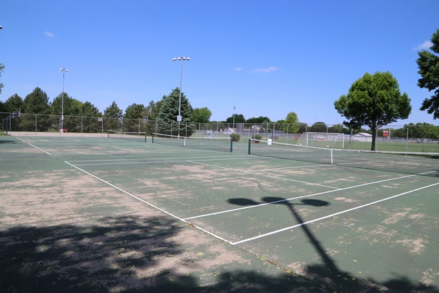 A tennis court with a tennis net and trees