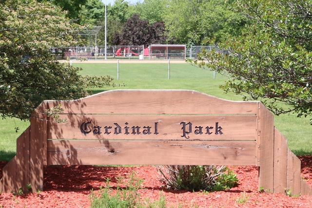 A wooden sign sitting in the middle of a park