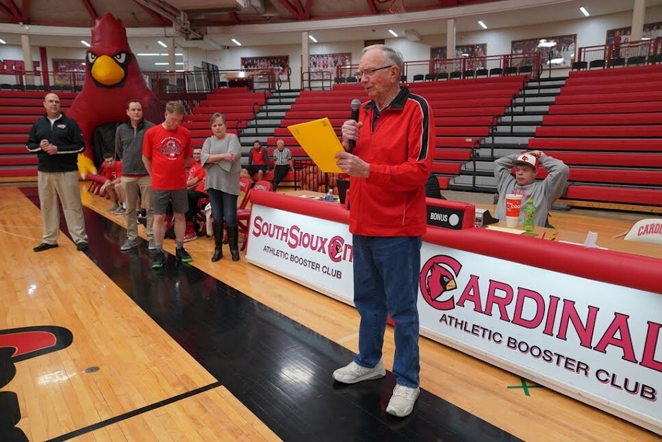 A man standing on a basketball court holding a piece of paper