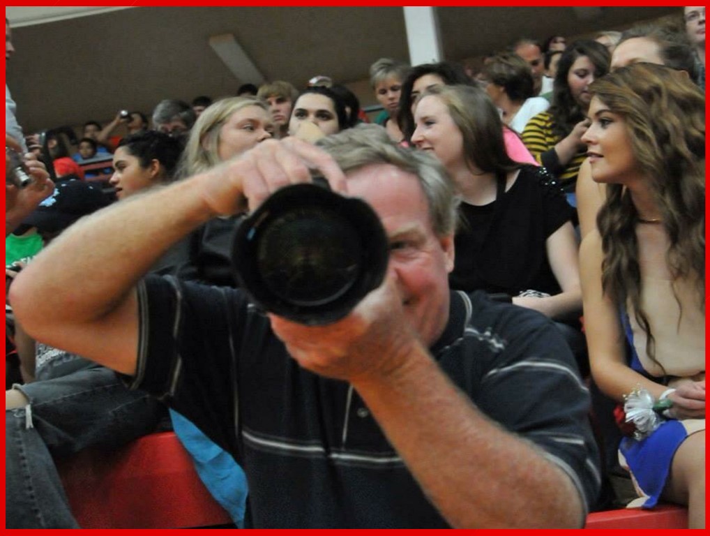 A man taking a picture with a camera in front of a crowd