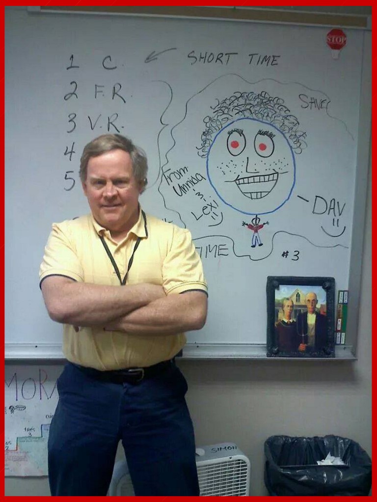 A man standing in front of a whiteboard with writing on it