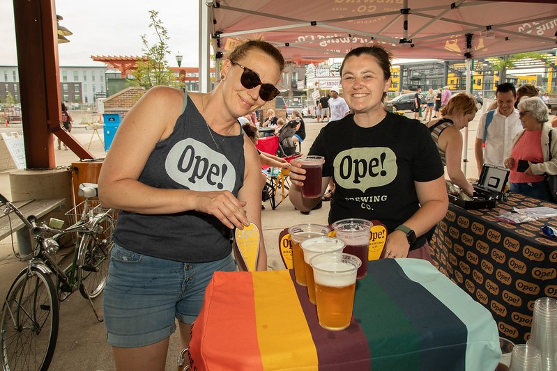 Two women enjoying beers at a table in West Allis, WI, sharing laughter and good times together.