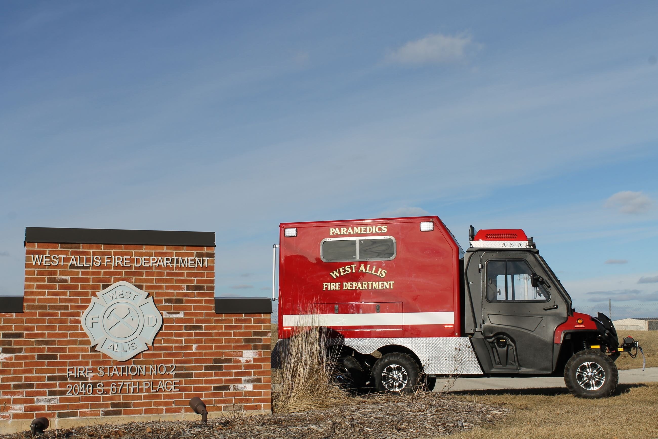 A red and black ambulance is parked in front of a brick building