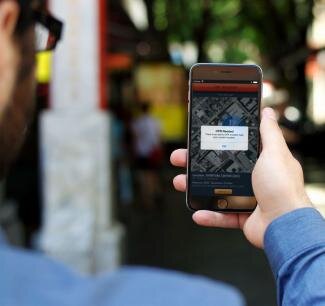 A man looks at his smartphone, which displays a map