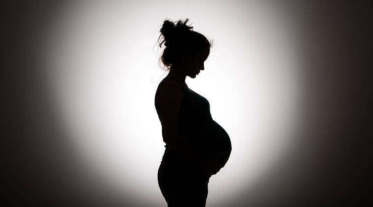 Silhouette of a pregnant woman against a dark background, symbolizing the importance of prenatal care coordination.