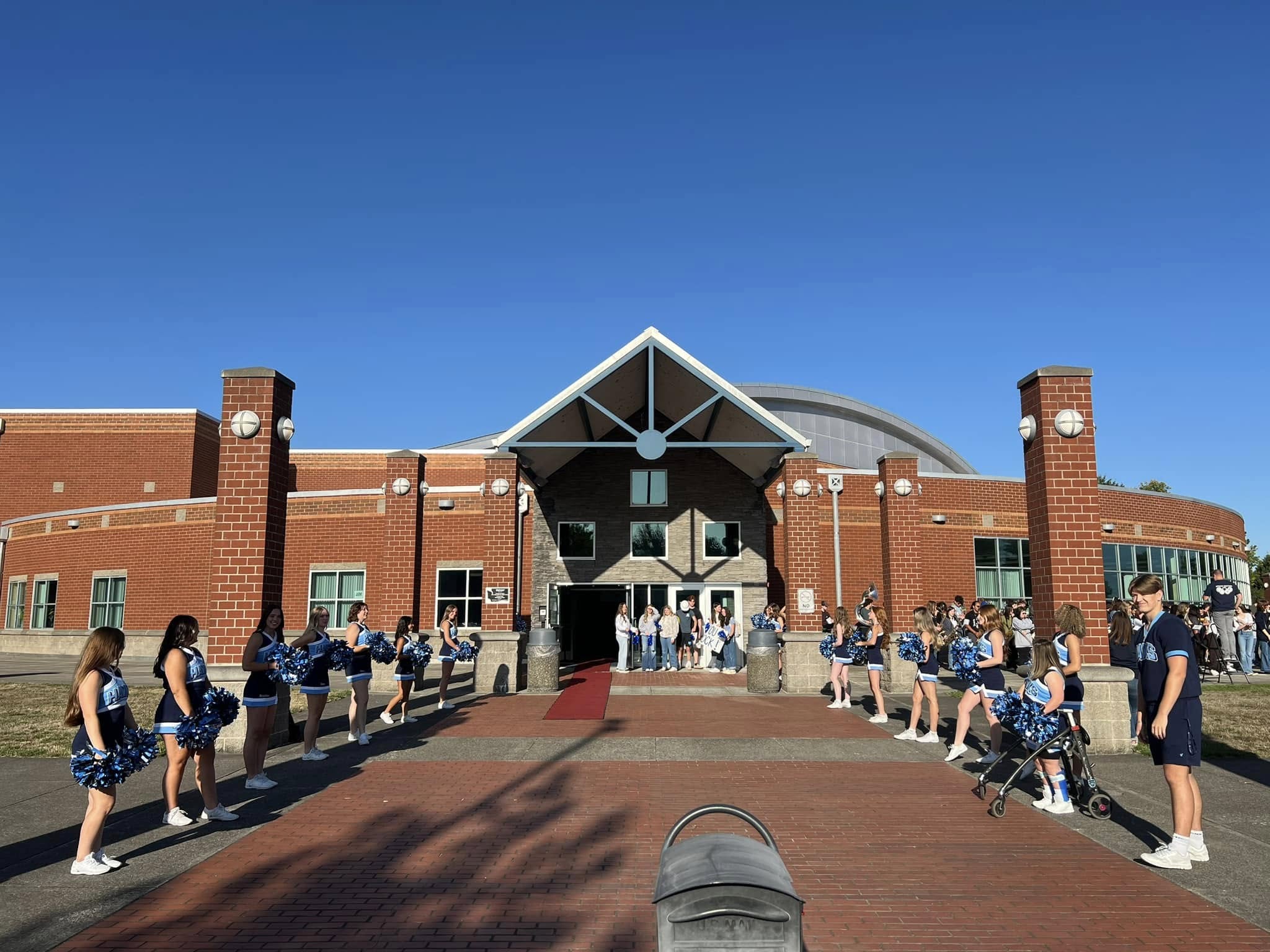 Hockinson High School building from exterior with cheer students on each side of the front door.