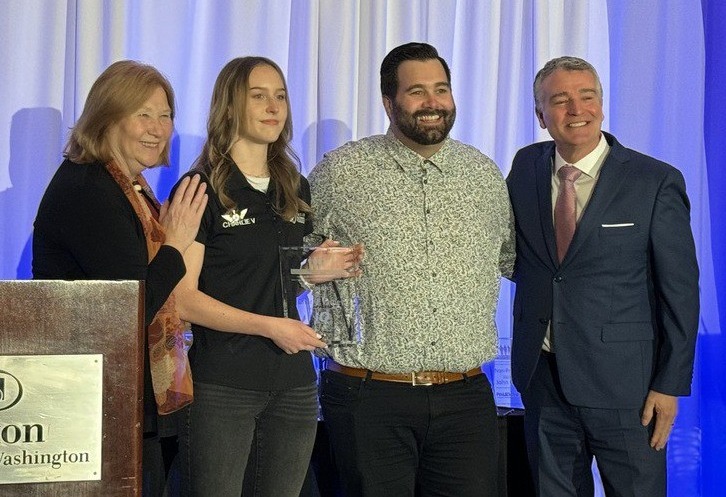 Mayor poses with senior student and two adults indoors.