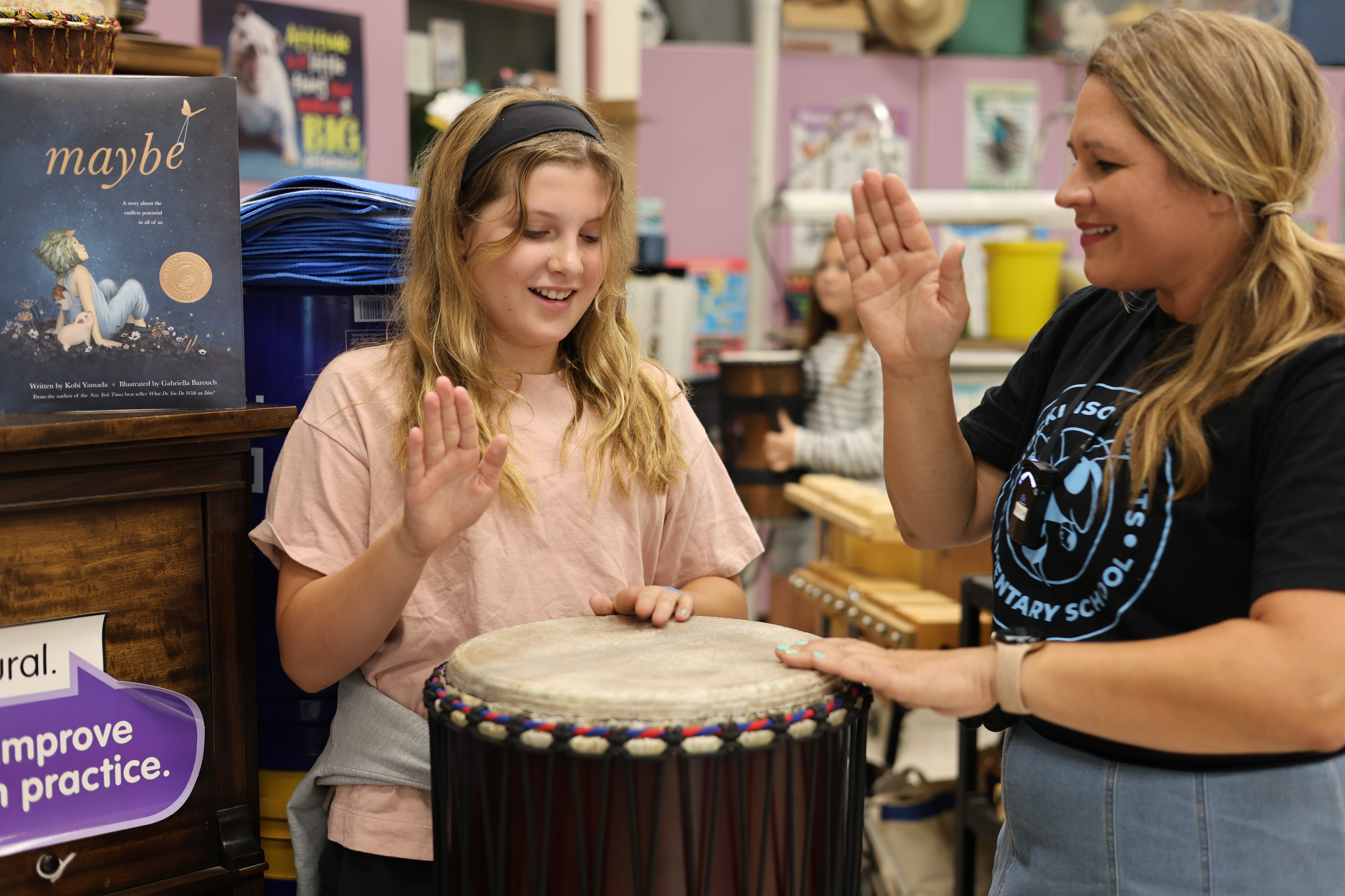Music teacher playing a drum with a student