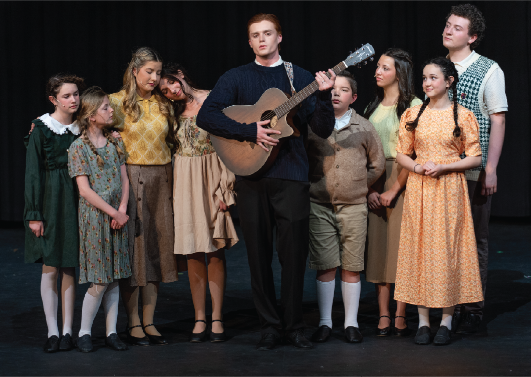 Student drama students on stage in costume with guitar