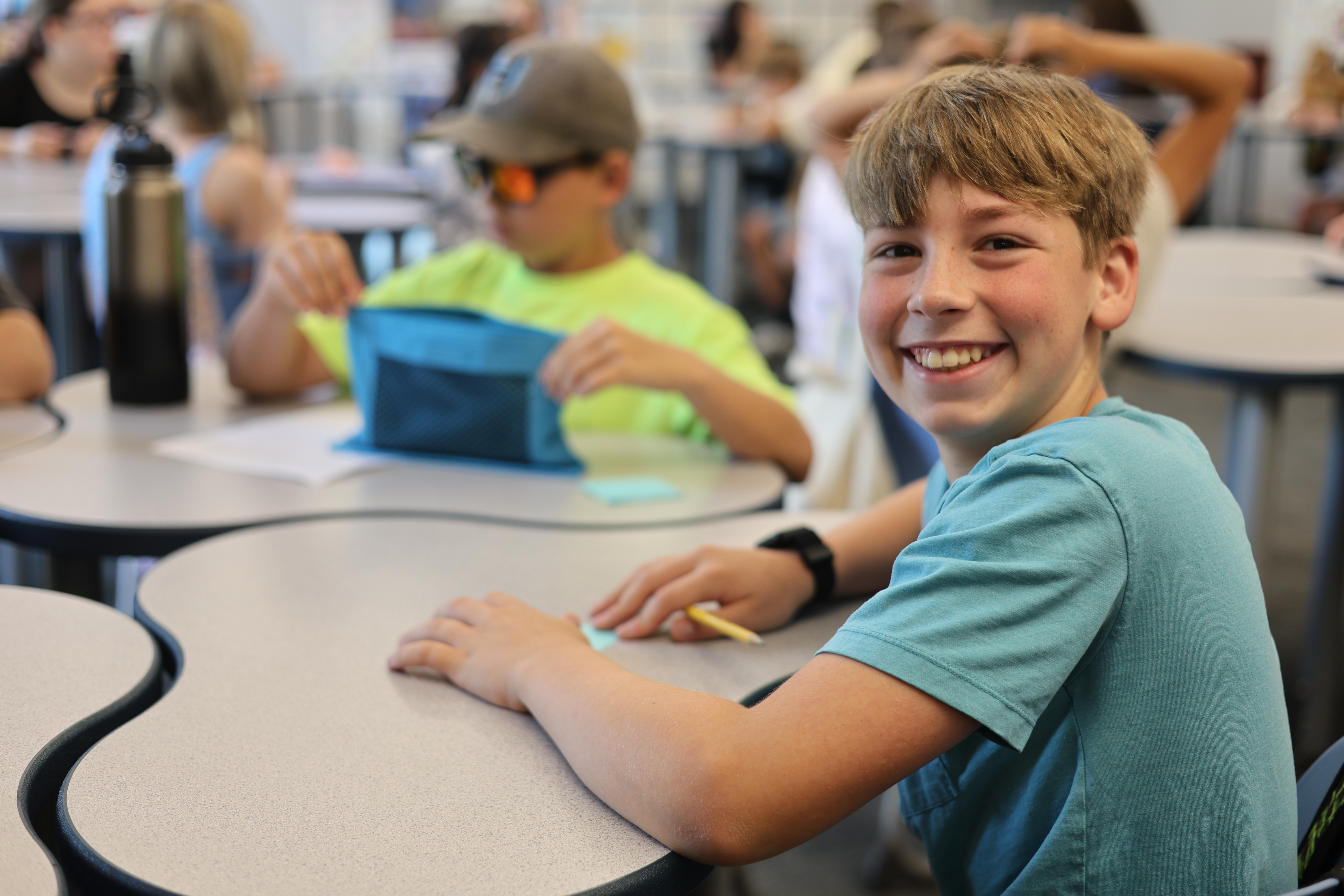 Student smiles at desk.
