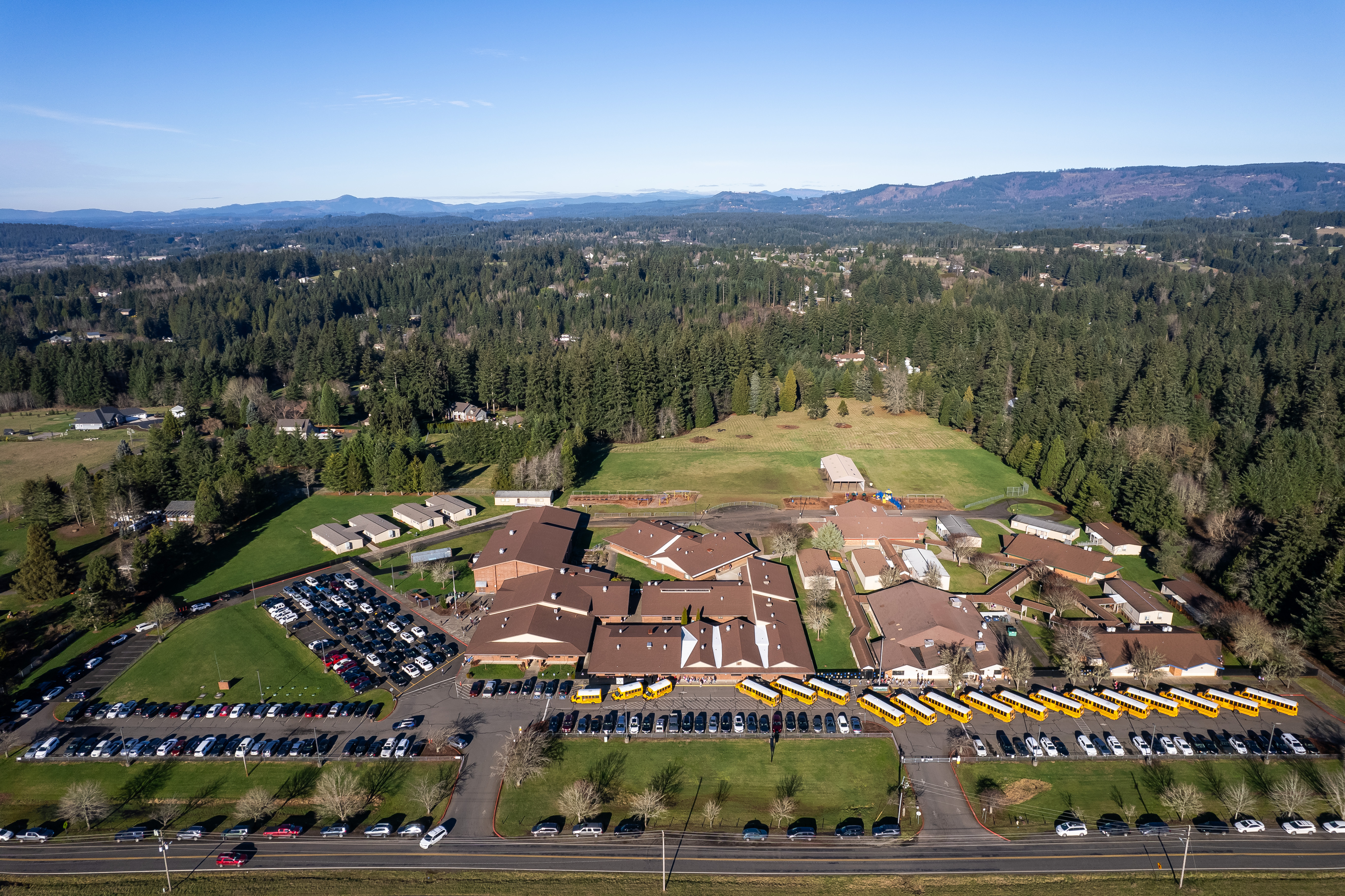 Aerial photo of school campus with row of buses at front.