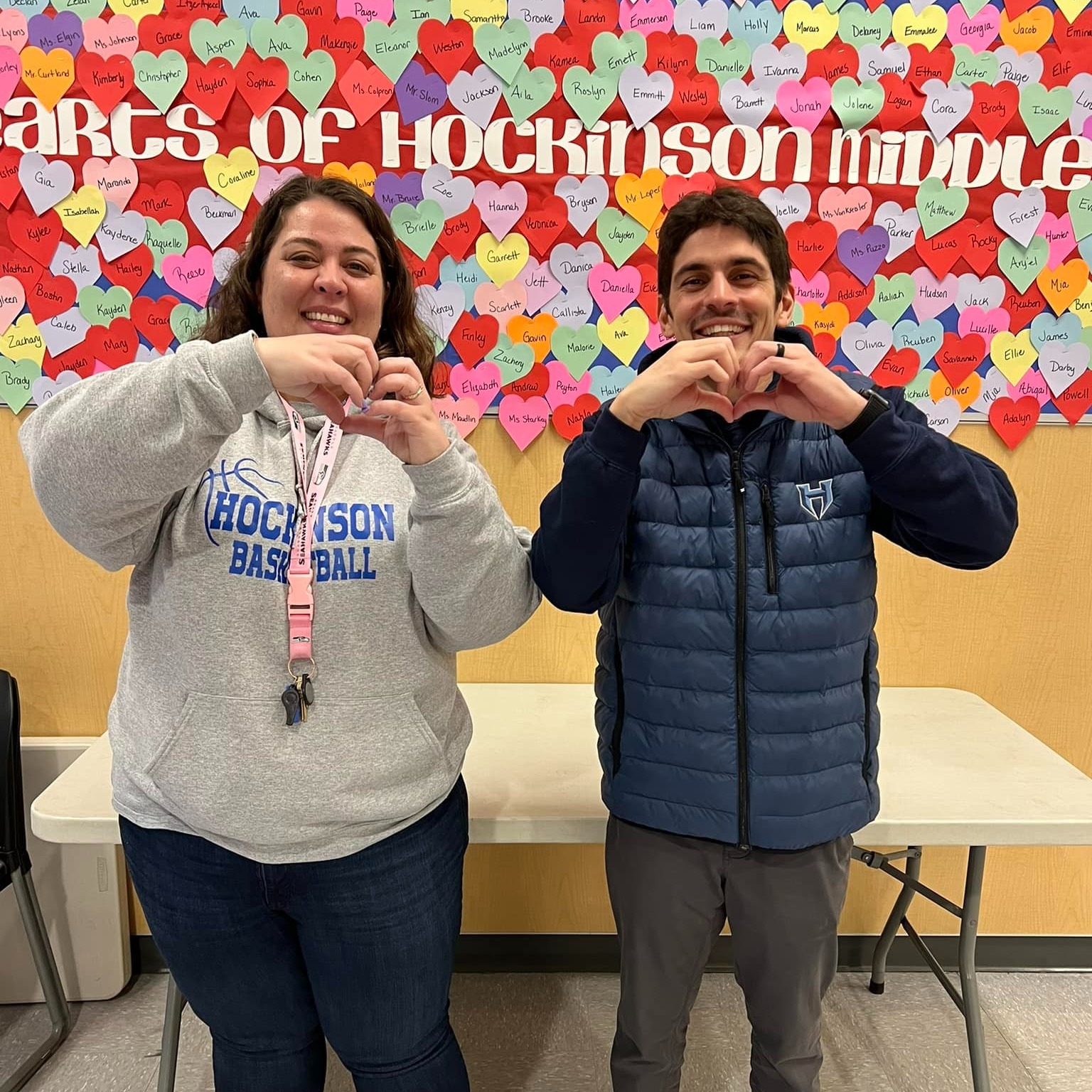 Two school leaders make hearts with their hands