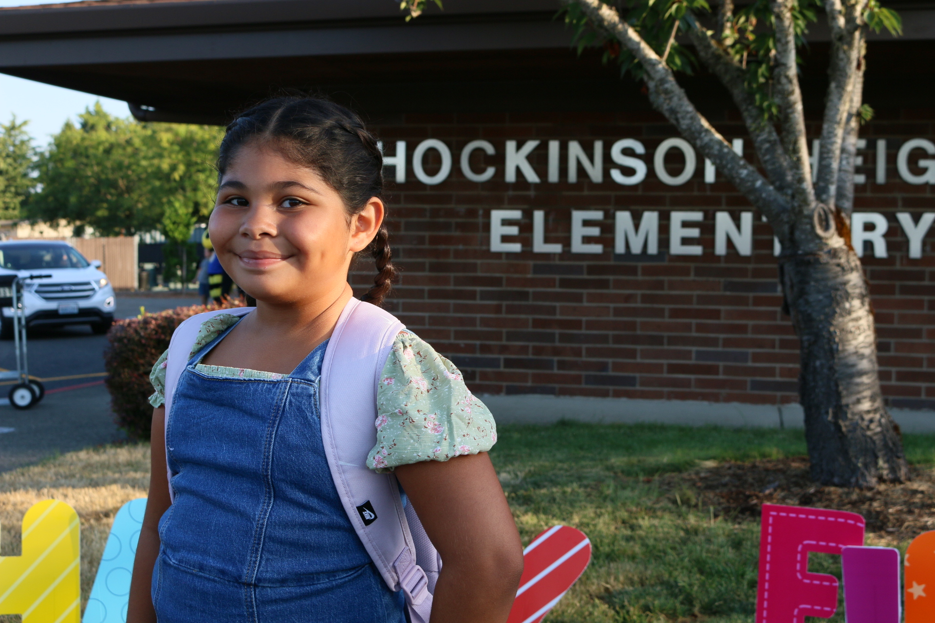 Young student stands in front of the Hockinson Heights Elementary School building.